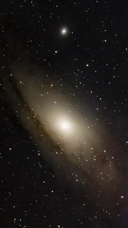 La galaxia de Andrómeda en tonos cálidos, con su núcleo brillante y las bandas de polvo entre las estrellas
