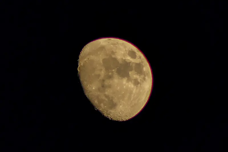 La Luna en fase gibosa con tonos ámbar sobre el cielo negro
