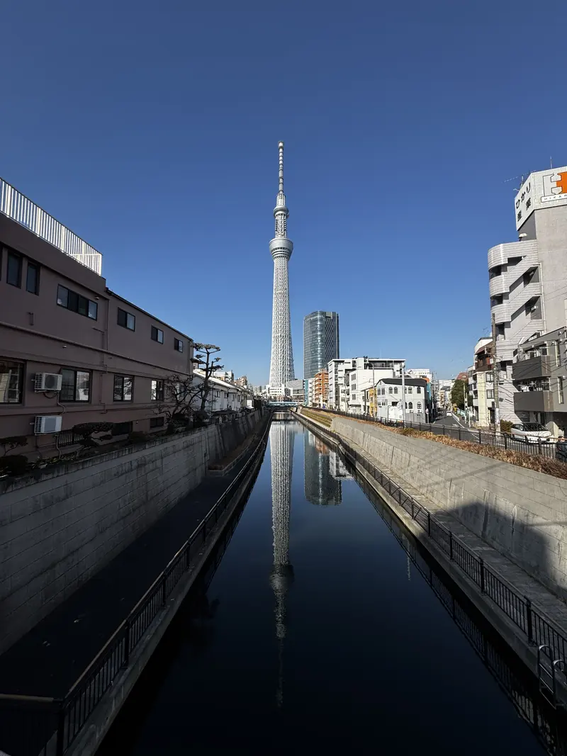 La torre Tokyo Skytree reflejada en el agua quieta de un canal