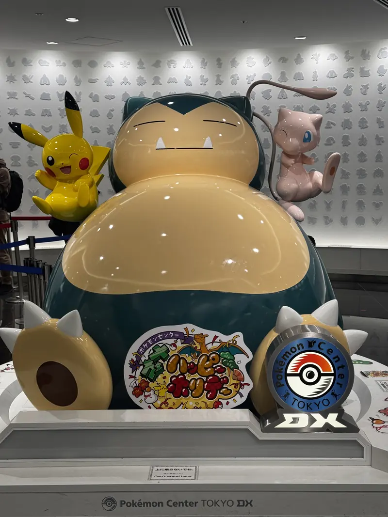Una figura grande de Snorlax acompañada de Pikachu y Mew en una tienda